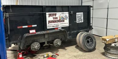 A black trailer for Jeff the Junkman with removed tires in a garage.