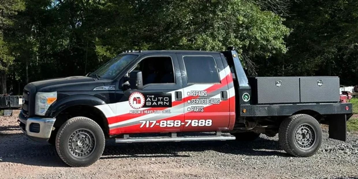 Black and red service truck for The Auto Barn with contact details and services listed.