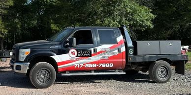 Black and red service truck for The Auto Barn with contact info.