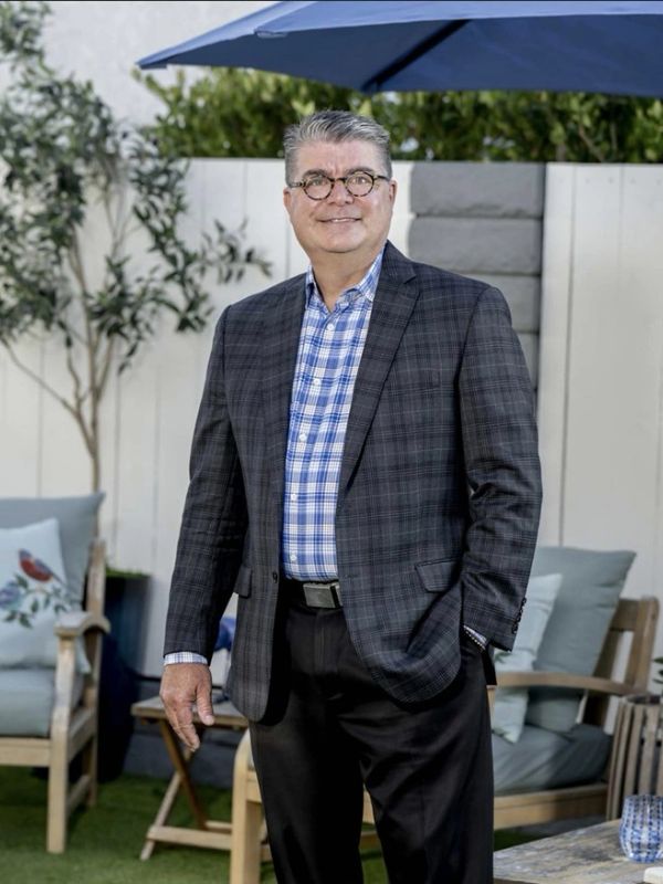 Man in a checked blazer and blue shirt outdoors.