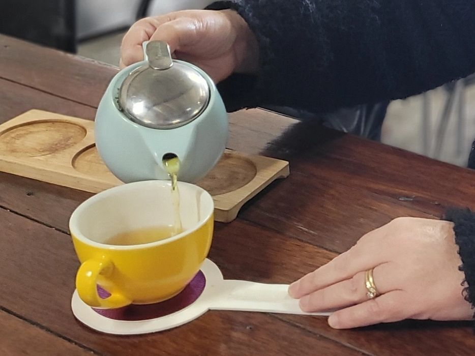 Sharon, our founder, pouring a cup of tea from a tea pot into a mug using an EziFind Coaster.