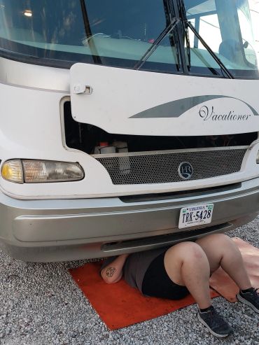 Person working under a recreational vehicle labeled Vacationer.