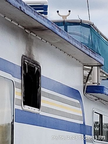 Close-up of a weathered ship with blue and yellow stripes.
