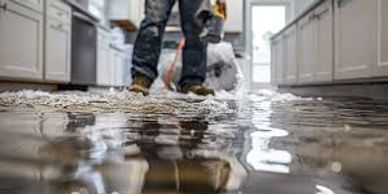 Person standing in a flooded kitchen with water covering the floor.