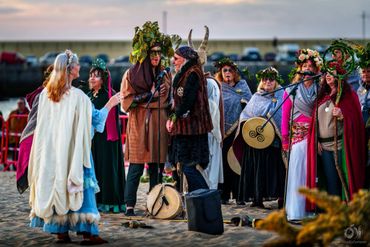 People in medieval-style costumes performing a ritual on the beach.