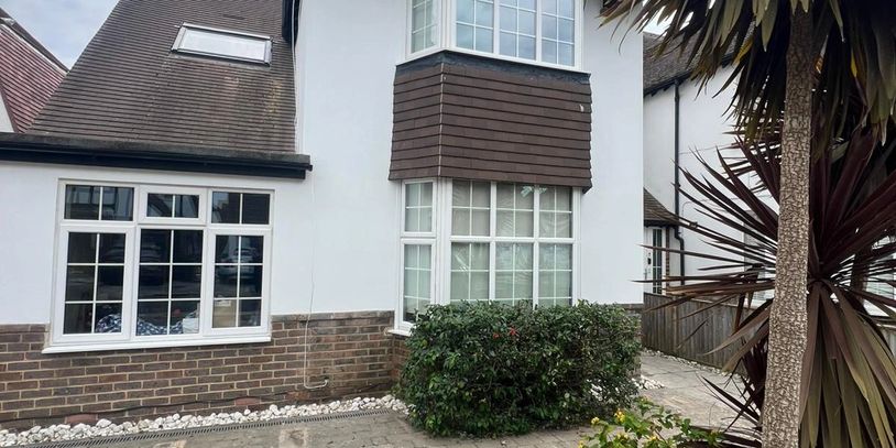 Exterior of a house with bay windows and a small garden in front.