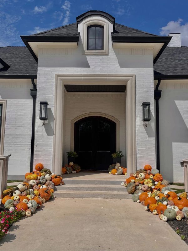 Front entrance of a house decorated with various pumpkins and gourds for fall.