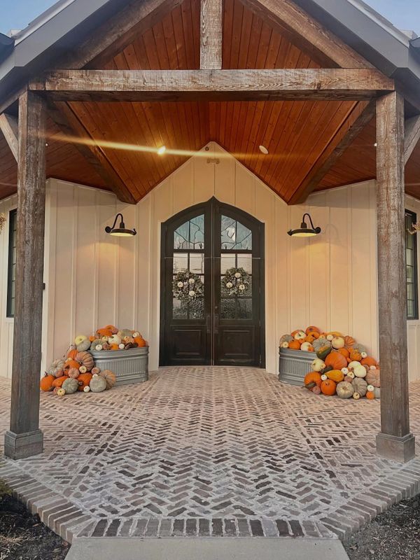 A cozy front porch with pumpkins and wooden beams under warm lighting.