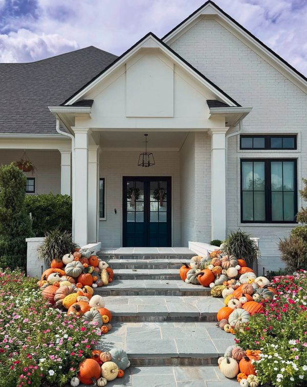 White house entrance decorated with colorful pumpkins and vibrant flowers.