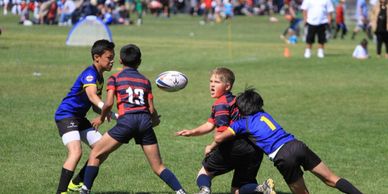Kids playing rugby outdoors on a sunny day.