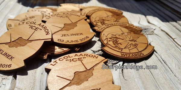 Wooden military challenge coins engraved with names and dates.