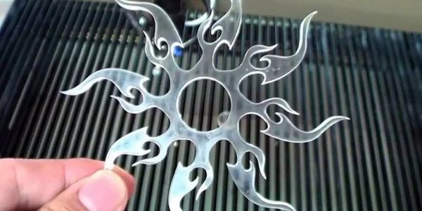 Hand holding a transparent plastic star-shaped object with flame-like extensions.