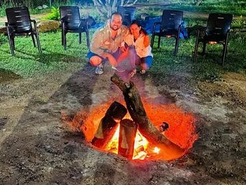 Guest enjoying and posing beside a warm fire camp at Namooru Ecostay.