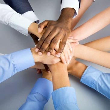 Diverse hands stacked in unity symbolizing teamwork.
