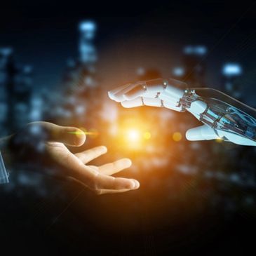 Human hand reaching out to robotic hand with glowing light between them.