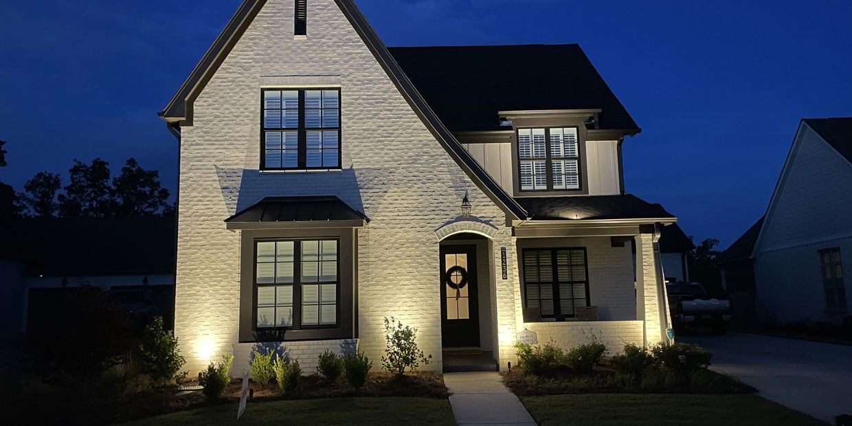 A well-lit modern house exterior at night with a dark sky.