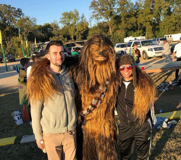 Two people posing with someone in a Chewbacca costume outdoors.