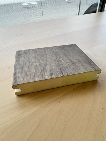 Foam core with wood grain laminate sample on a wooden table.