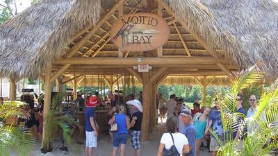 People gathered under a thatched roof bar named Mojito Bay.