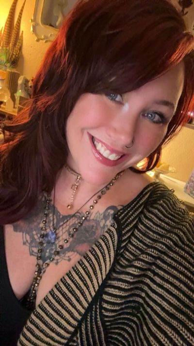 Smiling woman with red hair and tattoos.