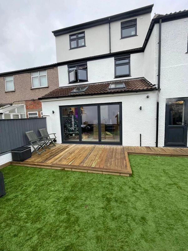 Modern backyard with wooden deck and green artificial grass.