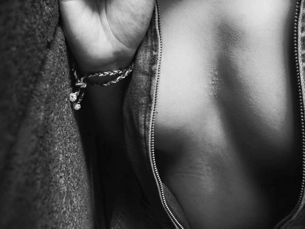 A black and white close-up photograph of a human torso partially framed by an open garment, focusing