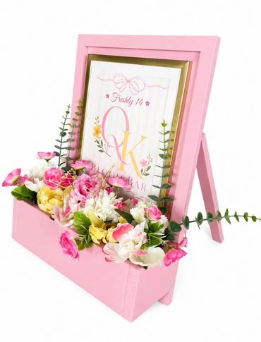 Pink floral photo frame with colorful artificial flowers.