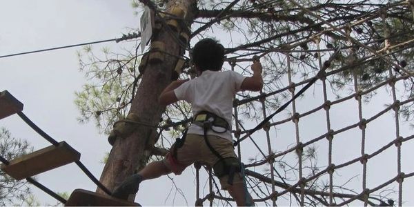 Child climbing an outdoor ropes course.