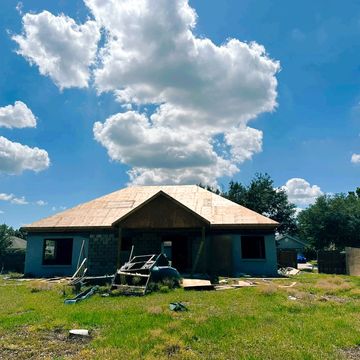 Partially constructed house under a blue sky with scattered clouds.