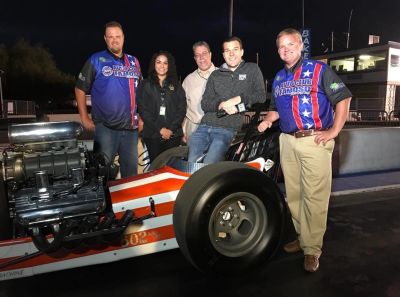 Group photo with dragster race car at night.