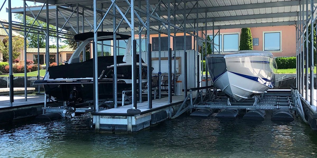Covered boat dock with two slips and a wakeboard boat and a offshore boat raised up out of the water