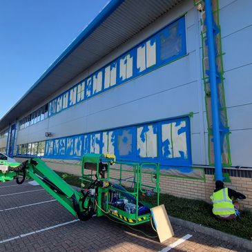 DecorDreams team using access equipment while painting the exterior of a commercial building.