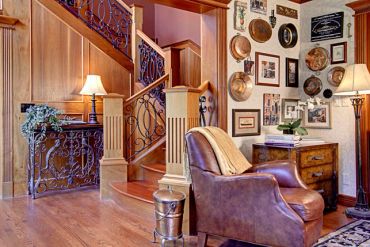 Cozy rustic living room with leather chair and wooden staircase.