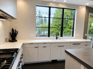 Modern kitchen with large window and black faucet.