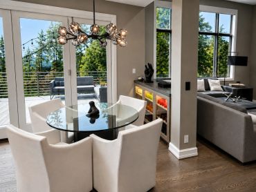 Modern dining area with glass table and white chairs.