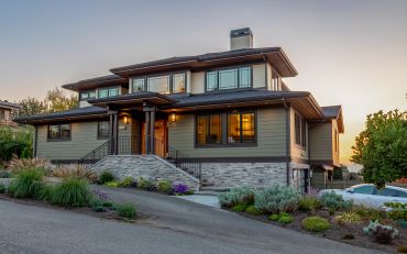 Modern two-story house with large windows and landscaped garden.