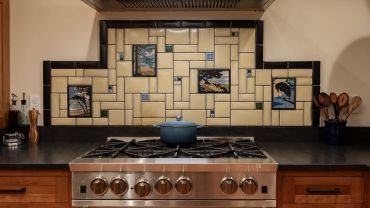 Decorative tiled backsplash behind a stove with cooking utensils.