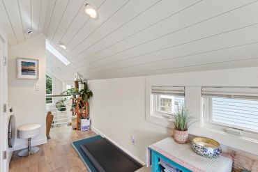 Bright, narrow attic space with plants and treadmill.