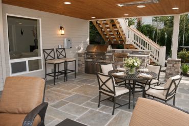 Covered outdoor patio with dining and grilling area.