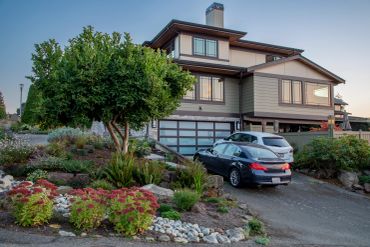 Modern two-story house with cars and landscaped garden.