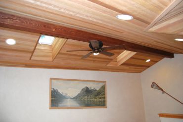 Ceiling with wooden beams, skylights, and a ceiling fan.