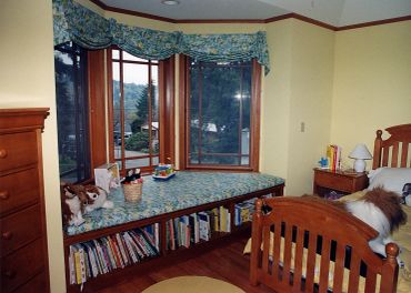 Cozy children's bedroom with wooden furniture and bay windows.