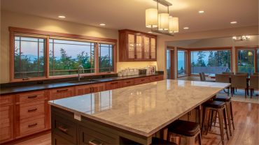 Modern kitchen with large island and scenic windows.