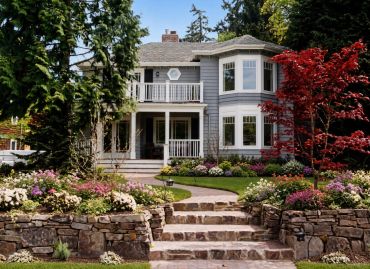 Beautiful blue house with colorful garden and stone steps.