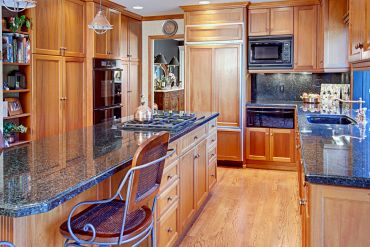 Cozy kitchen with wooden cabinets and dark granite countertops.