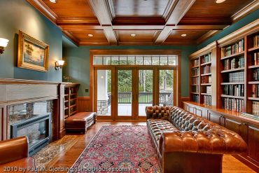 Cozy library with leather sofa and fireplace.