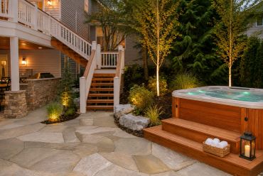 Cozy backyard with hot tub and stone patio at dusk.