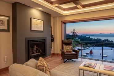 Cozy living room with fireplace and ocean view at sunset.