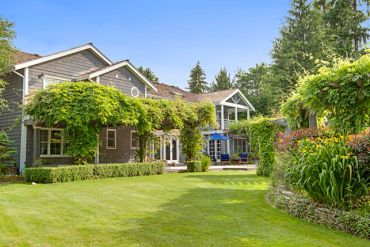 Large house with lush green garden and vine-covered pergolas.