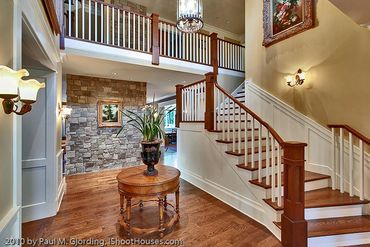 Elegant wooden staircase with white railings in a spacious foyer.